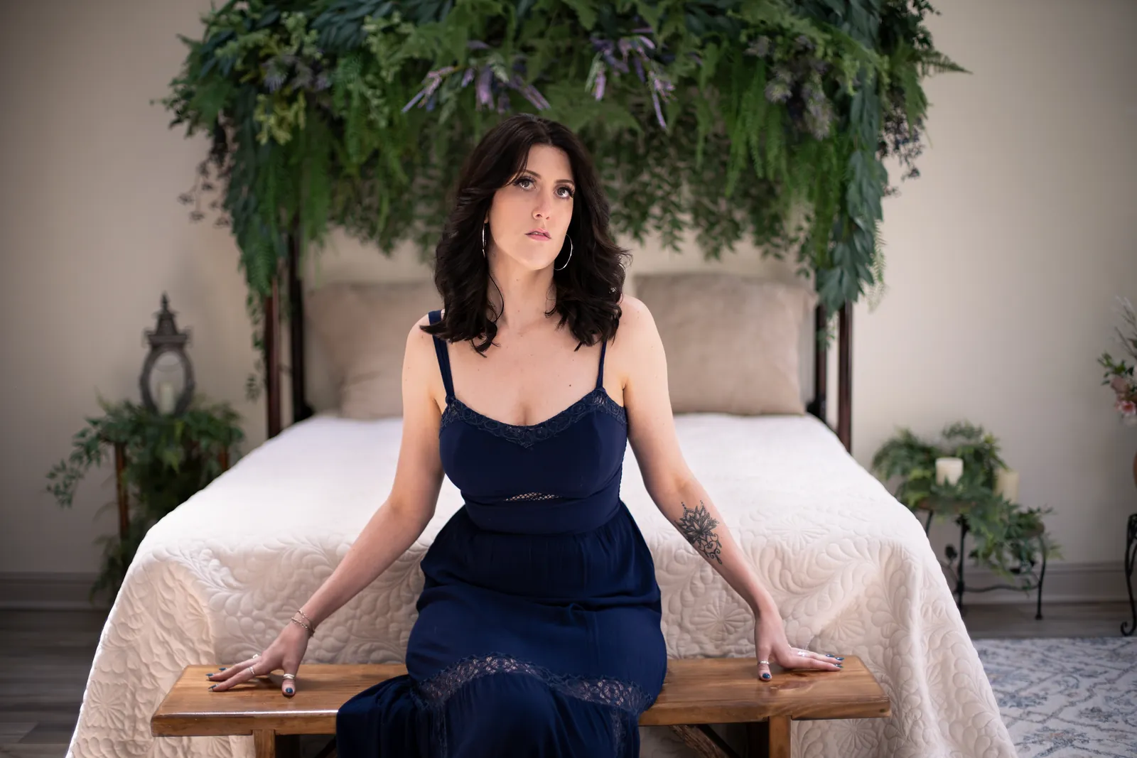 woman in an elegant navy dress seated confidently on a canopy bed during an empowerment photography session at laurel hollow studio
